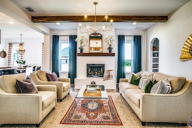 living room featuring a wealth of natural light, a brick fireplace, beam ceiling, and an inviting chandelier