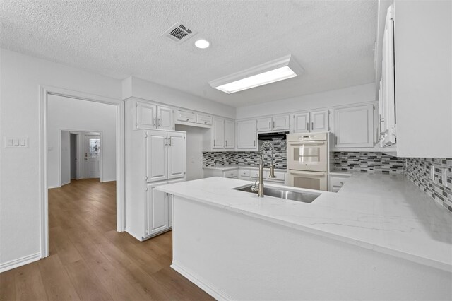 kitchen featuring sink, white cabinets, light hardwood / wood-style flooring, and kitchen peninsula