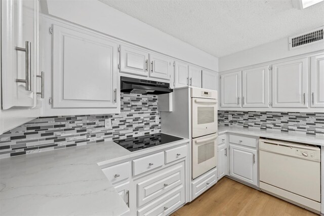 kitchen featuring white appliances, white cabinetry, light hardwood / wood-style flooring, and decorative backsplash