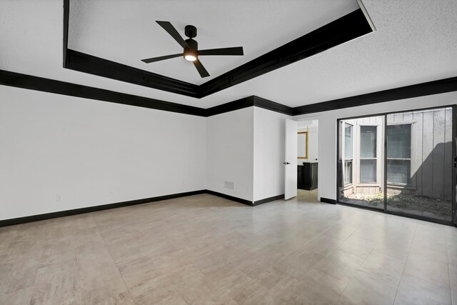 spare room with ceiling fan, a raised ceiling, a textured ceiling, and ornamental molding