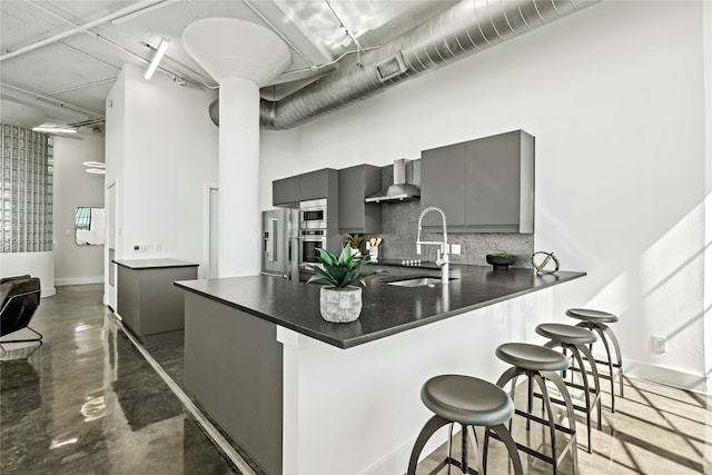 kitchen featuring sink, gray cabinets, appliances with stainless steel finishes, a kitchen bar, and kitchen peninsula