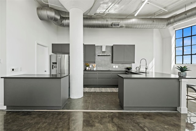 kitchen featuring wall chimney exhaust hood, sink, tasteful backsplash, high quality fridge, and gray cabinets