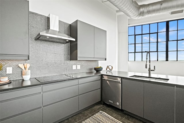 kitchen with wall chimney range hood, sink, gray cabinets, dishwasher, and cooktop