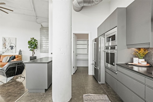 kitchen with tasteful backsplash, appliances with stainless steel finishes, dark tile patterned floors, and gray cabinetry