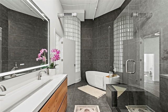 bathroom featuring vanity, tile patterned flooring, plus walk in shower, and tile walls