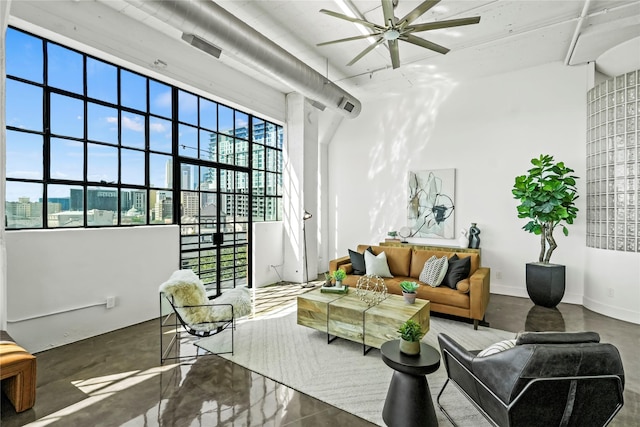 living room featuring concrete flooring, a high ceiling, and ceiling fan