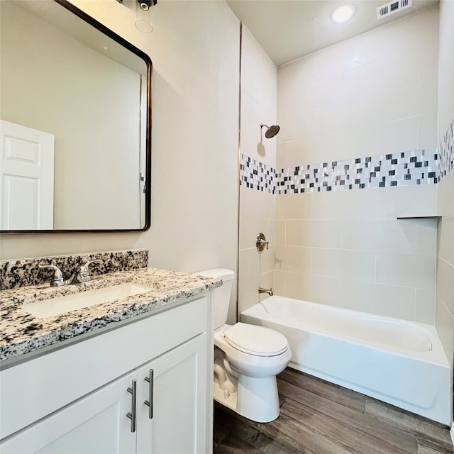 full bathroom with vanity, toilet, tiled shower / bath, and hardwood / wood-style floors