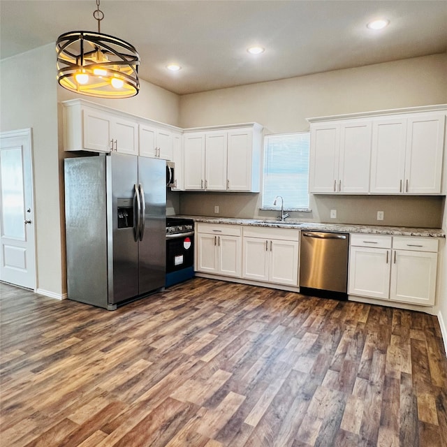 kitchen with sink, stainless steel appliances, decorative light fixtures, white cabinets, and a notable chandelier