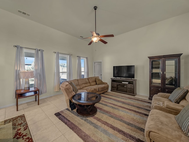 living room featuring a towering ceiling, ceiling fan, and light tile patterned floors