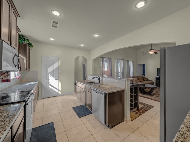 kitchen with tasteful backsplash, sink, dark brown cabinets, ceiling fan, and stainless steel appliances