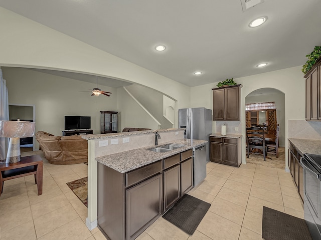 kitchen with appliances with stainless steel finishes, sink, dark brown cabinets, lofted ceiling, and a center island with sink