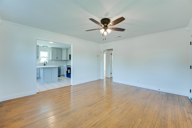 empty room featuring light hardwood / wood-style flooring, ornamental molding, and ceiling fan