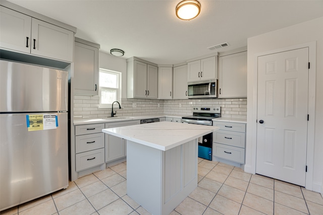 kitchen featuring sink, a kitchen island, stainless steel appliances, light stone counters, and light tile patterned floors