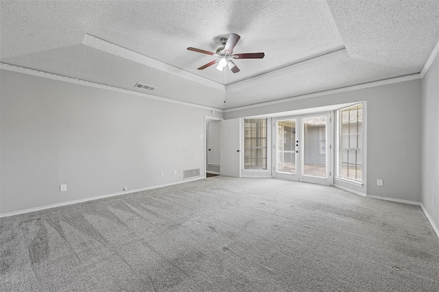 carpeted empty room with french doors, a textured ceiling, a tray ceiling, and ceiling fan