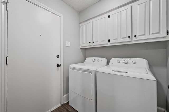 washroom with cabinets, washer and dryer, a textured ceiling, and dark hardwood / wood-style flooring