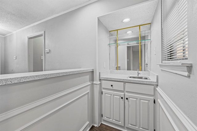 bathroom with vanity, ornamental molding, hardwood / wood-style flooring, and a textured ceiling