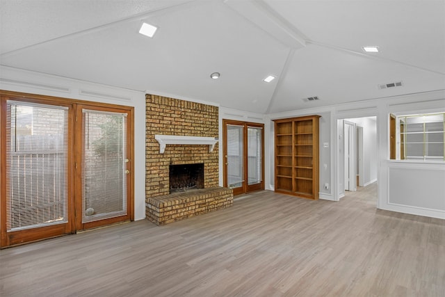 unfurnished living room with a fireplace, lofted ceiling with beams, and light wood-type flooring