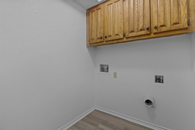 washroom with hookup for an electric dryer, light hardwood / wood-style flooring, hookup for a washing machine, and cabinets