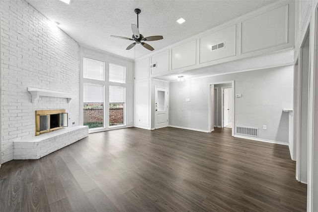 unfurnished living room with ceiling fan, dark hardwood / wood-style flooring, a textured ceiling, a fireplace, and a towering ceiling