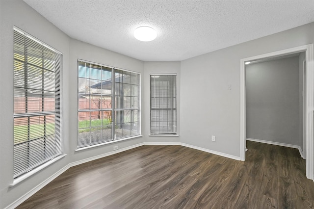 unfurnished room with dark wood-type flooring and a textured ceiling