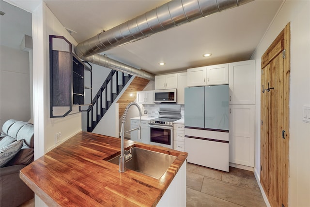 kitchen featuring stainless steel appliances, white cabinetry, light tile patterned floors, decorative backsplash, and sink