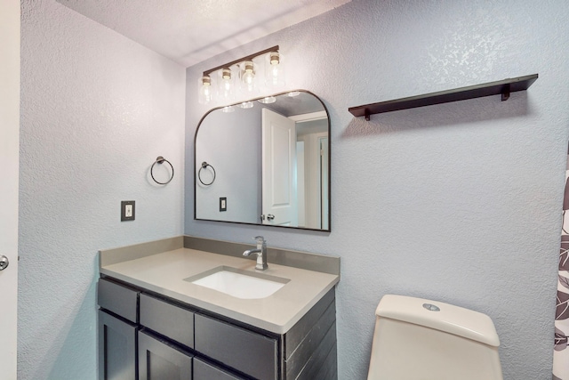 bathroom featuring vanity, toilet, and a textured ceiling