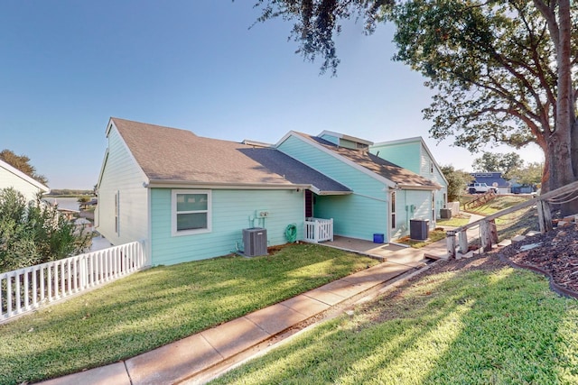 back of property with a lawn and central AC