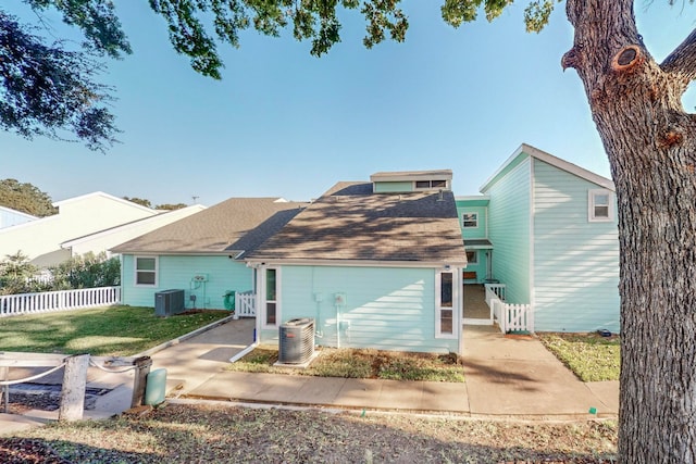 rear view of property featuring cooling unit and a lawn