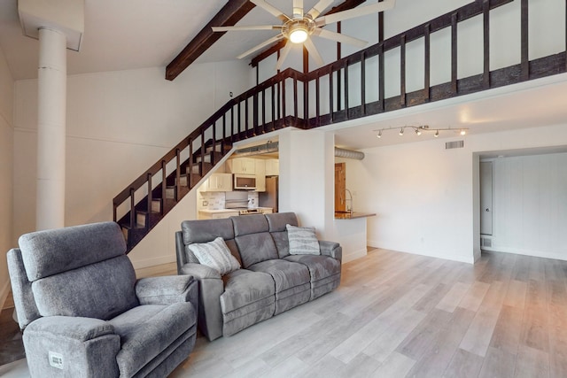 living room with light wood-type flooring, vaulted ceiling with beams, and ceiling fan