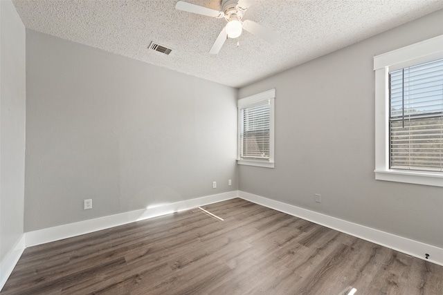 spare room with ceiling fan, a textured ceiling, and dark hardwood / wood-style floors