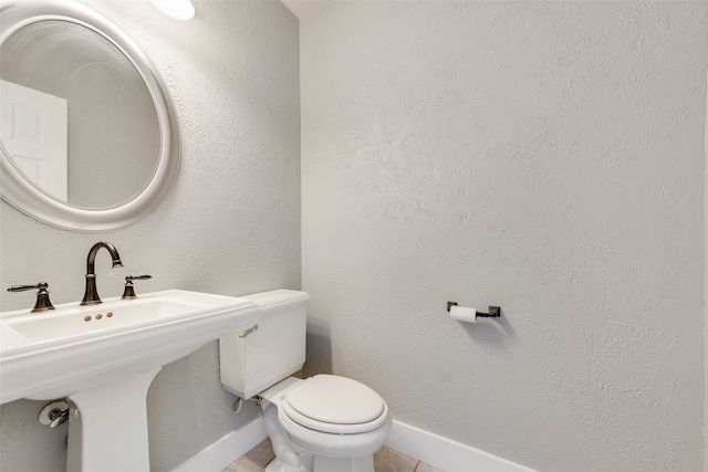 bathroom featuring toilet, sink, and tile patterned flooring