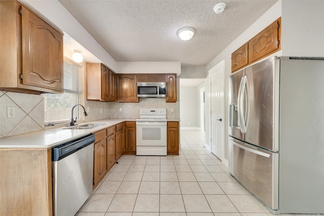 kitchen featuring appliances with stainless steel finishes, sink, a textured ceiling, decorative backsplash, and light tile patterned floors