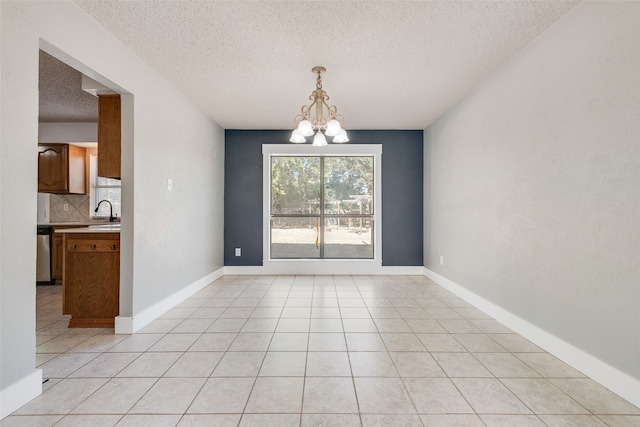 unfurnished dining area featuring sink, a textured ceiling, light tile patterned floors, and a chandelier