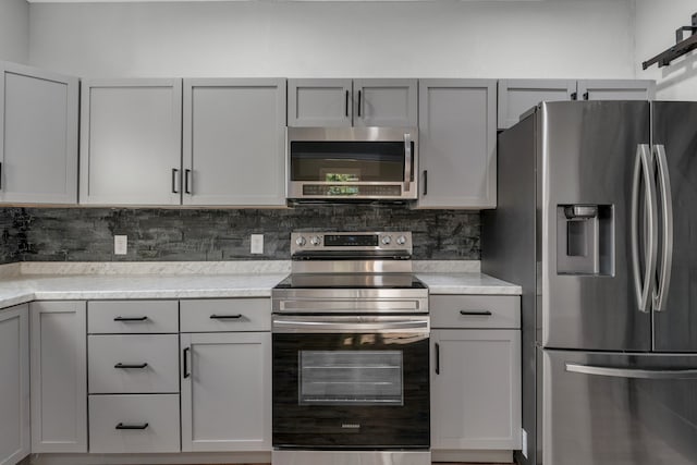 kitchen featuring light stone counters, appliances with stainless steel finishes, decorative backsplash, and gray cabinets