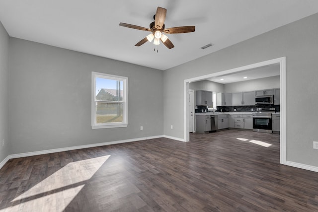 unfurnished living room featuring ceiling fan and dark hardwood / wood-style flooring