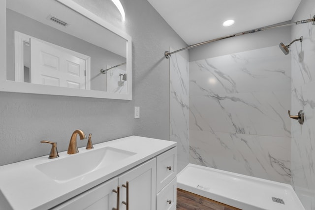 bathroom with vanity, wood-type flooring, and tiled shower