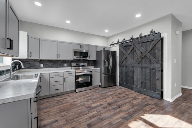 kitchen with sink, a barn door, dark wood-type flooring, and stainless steel appliances