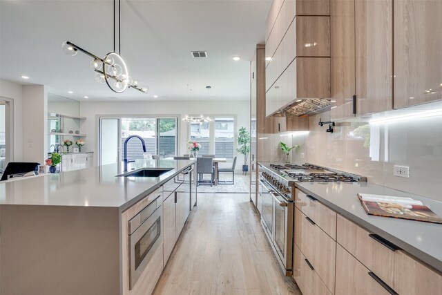 kitchen with a spacious island, light hardwood / wood-style flooring, stainless steel appliances, and a notable chandelier