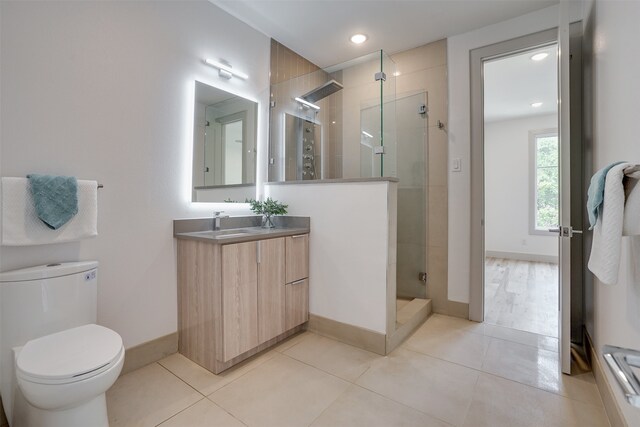 bathroom with a shower with door, vanity, toilet, and tile patterned flooring