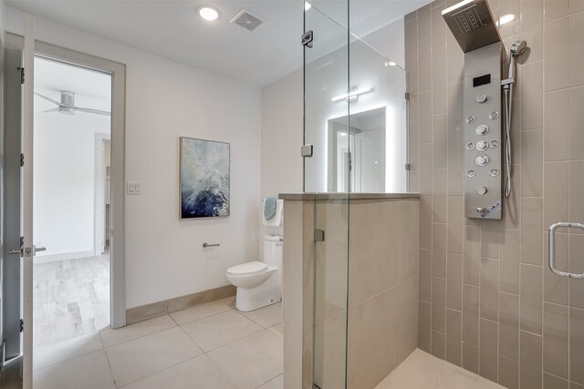 bathroom featuring tile patterned floors, ceiling fan, toilet, and an enclosed shower