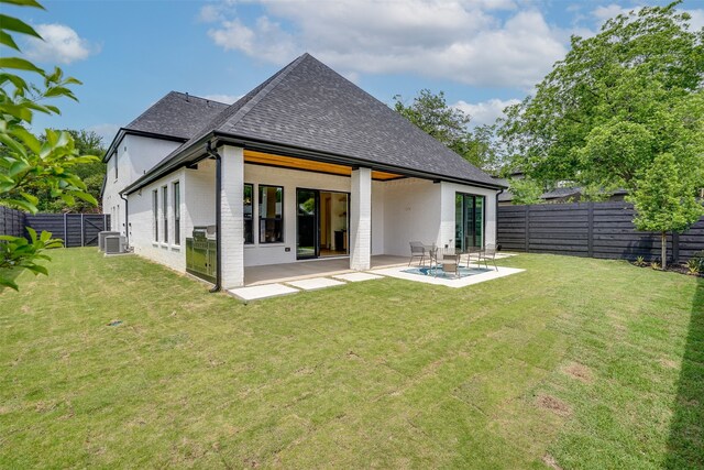 rear view of house with a patio, cooling unit, and a lawn