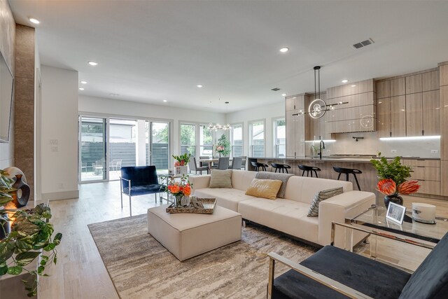 living room featuring a chandelier and light wood-type flooring