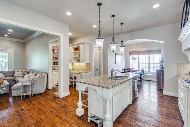 kitchen with a center island with sink, white cabinets, dark hardwood / wood-style floors, and a healthy amount of sunlight