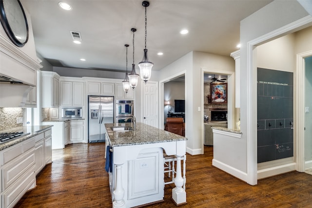 kitchen featuring white cabinetry, appliances with stainless steel finishes, and an island with sink