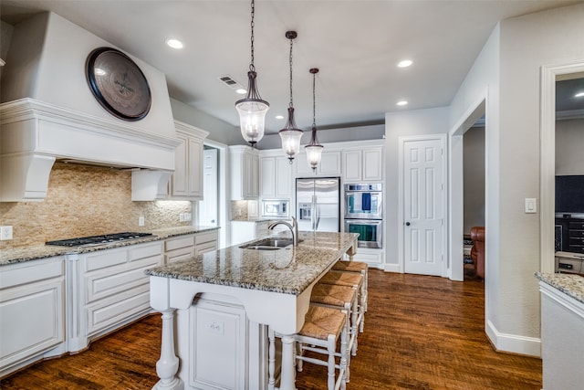 kitchen featuring sink, dark hardwood / wood-style flooring, stainless steel appliances, a breakfast bar, and a kitchen island with sink