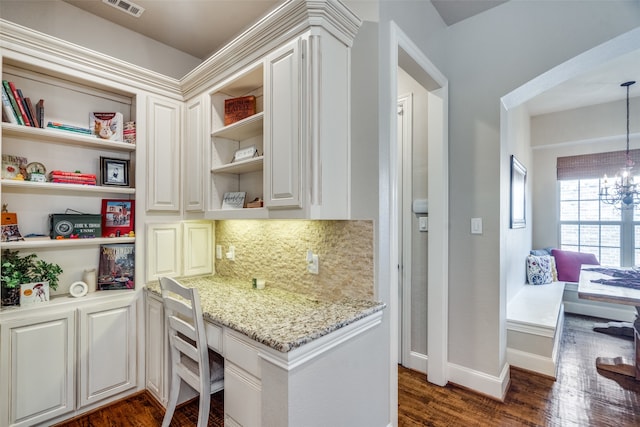 kitchen featuring dark wood-type flooring, light stone countertops, a chandelier, and white cabinets