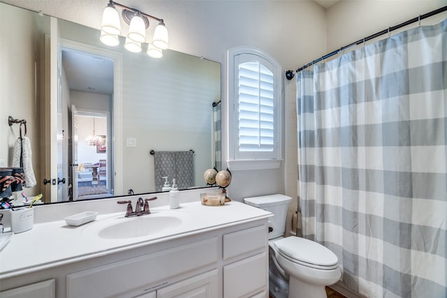 bathroom featuring toilet, a notable chandelier, curtained shower, and vanity