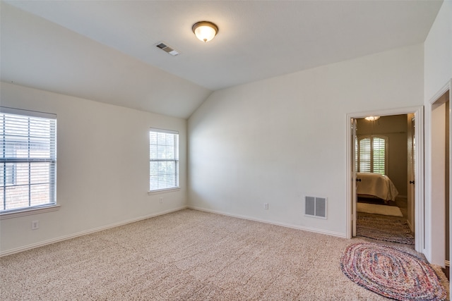 carpeted empty room with lofted ceiling and a wealth of natural light