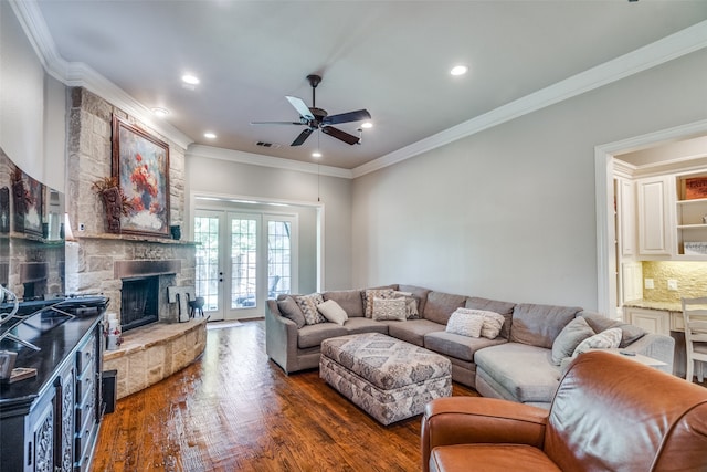 living room featuring french doors, a stone fireplace, dark hardwood / wood-style flooring, ceiling fan, and ornamental molding