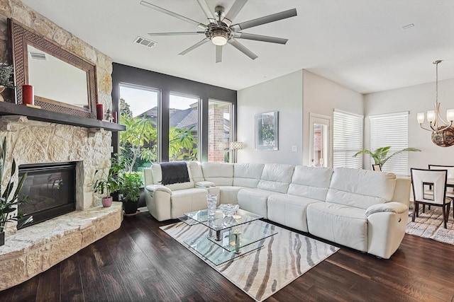 living room with ceiling fan with notable chandelier, a fireplace, and dark hardwood / wood-style flooring